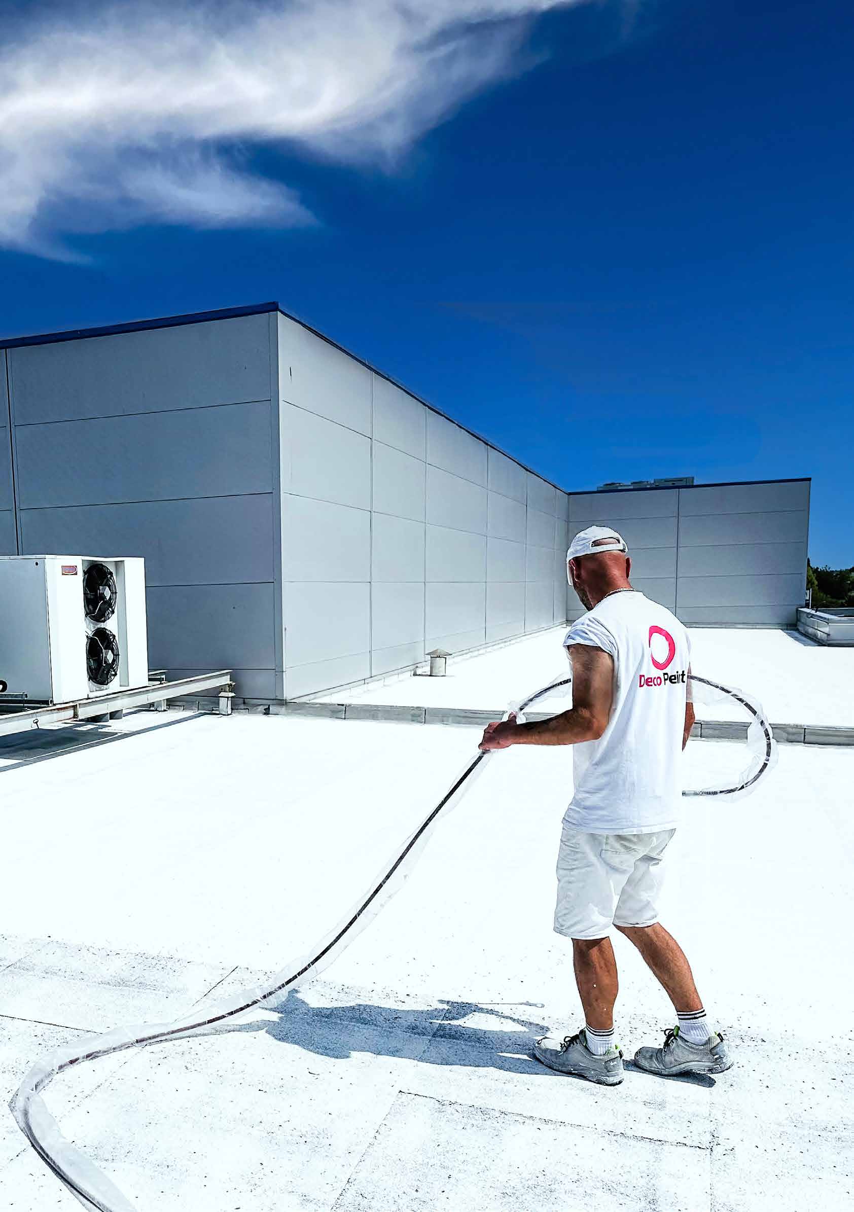 Application professionnelle d’une peinture réflective blanche sur une toiture
