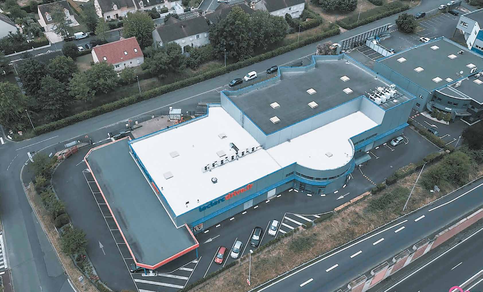 Vue aérienne d’une toiture de commerce en cours d’application d’un revêtement blanc réflectif près d’Orléans